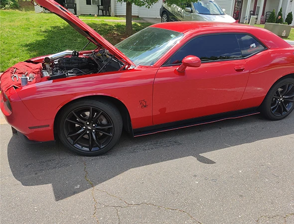 Same-day mobile battery replacement for a red sports car in Charlotte, NC, performed at the customer's location.