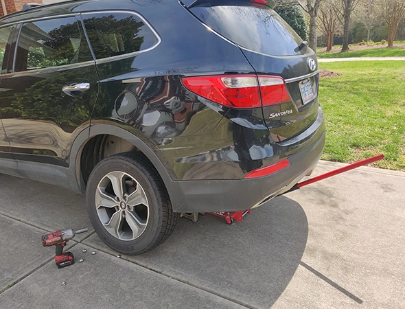 Allstar Mobile Mechanic technician performing a tire and suspension check on a black SUV in a residential driveway in Concord, NC.