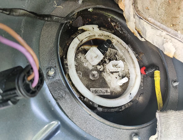 Close-up view of a dirty car suspension component or fuel pump assembly housing being inspected with professional diagnostic tools in Huntersville, NC.