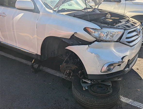 White SUV with front-end damage and wheel removed for strut repair and replacement services in Charlotte, NC.