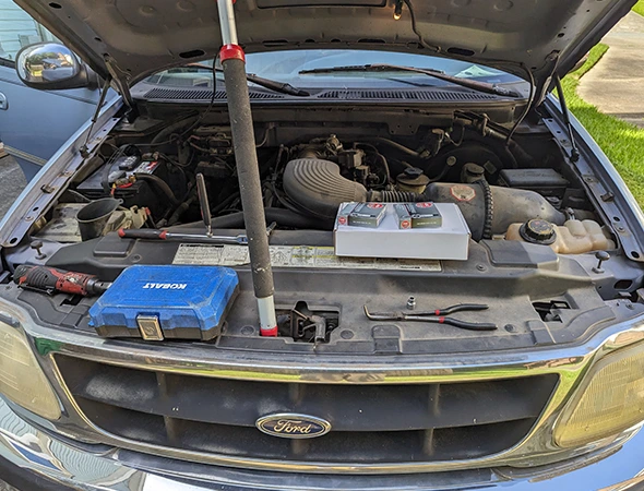 Mechanic tools and replacement parts positioned on a Ford truck engine bay for sensor replacement services in Salisbury, NC.