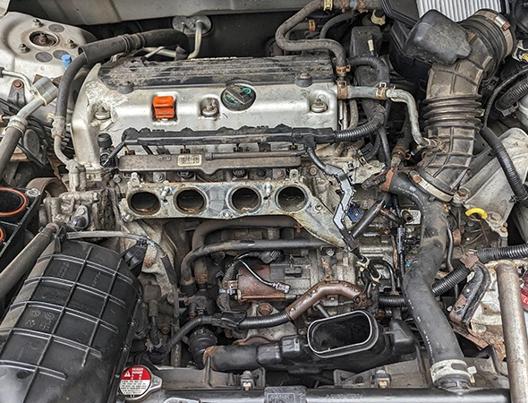 Close-up overhead view of a car engine bay and intake manifold undergoing a professional cooling system flush and refill service in Concord, NC.